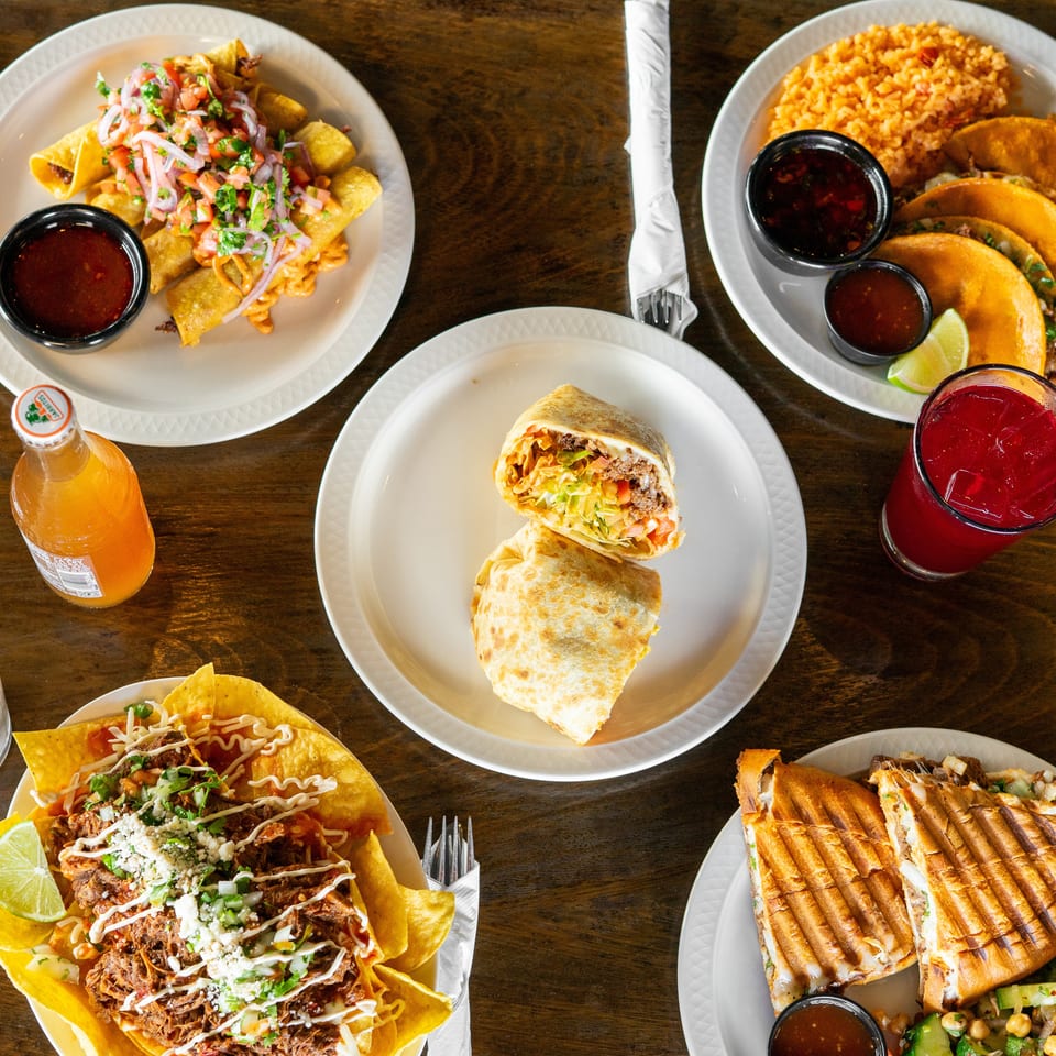Overhead view of a wooden table laden with various Mexican dishes and drinks.